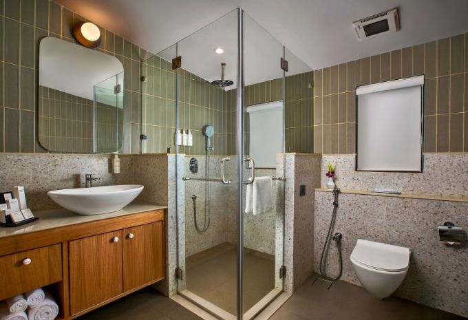 Bathroom with terrazzo shower, vessel sink and sage green tiled walls at Mercure Goa Devaaya Resort