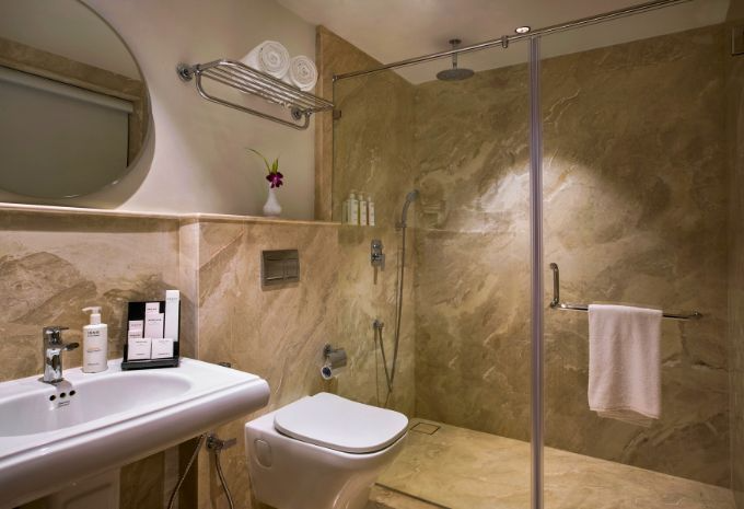 Marble bathroom with ceiling rainfall shower and luxury toiletries at Mercure Goa Devaaya Resort
