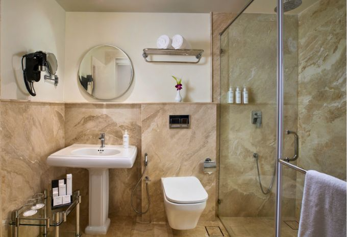 Modern bathroom with walk-in shower and curved wooden vanity at Mercure Goa Devaaya Resort Divar Island