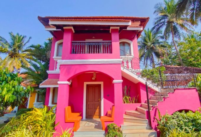Two-storey pink Portuguese-style villa with wrought iron balcony at Mercure Goa Devaaya Resort Divar Island